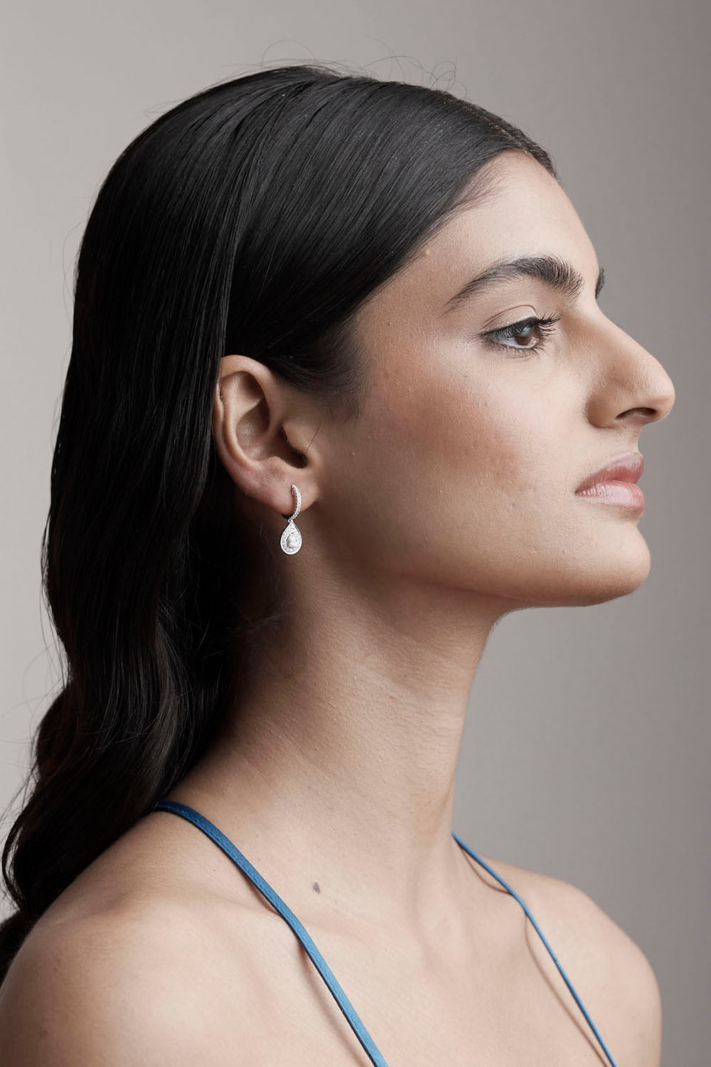 Woman wearing a silver earring with a neutral background