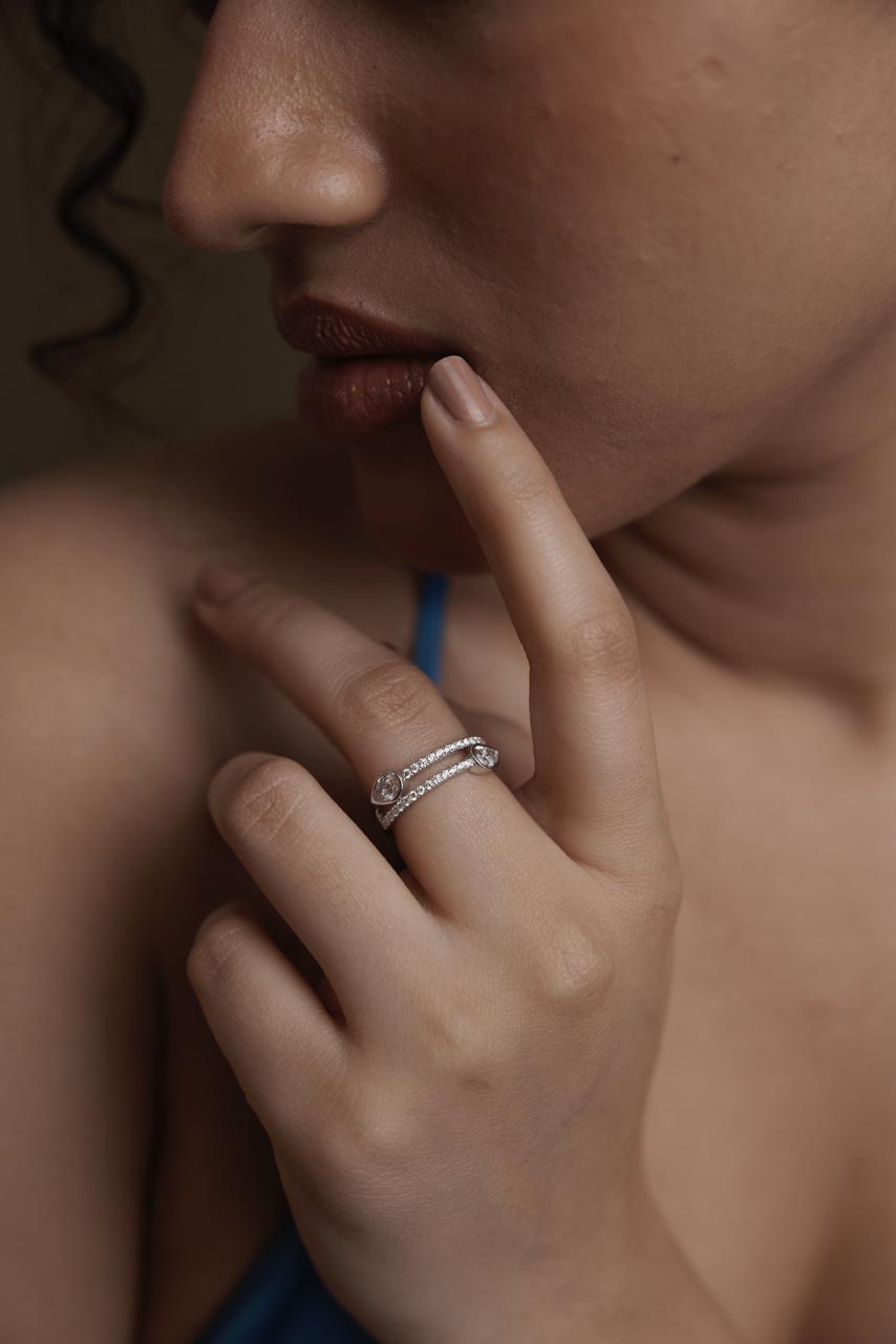 Close-up of a person's hand with a ring, touching their lips.